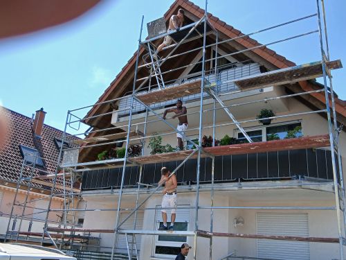 Handwerker bei Fassadenarbeiten am eingerüsteten Giebel